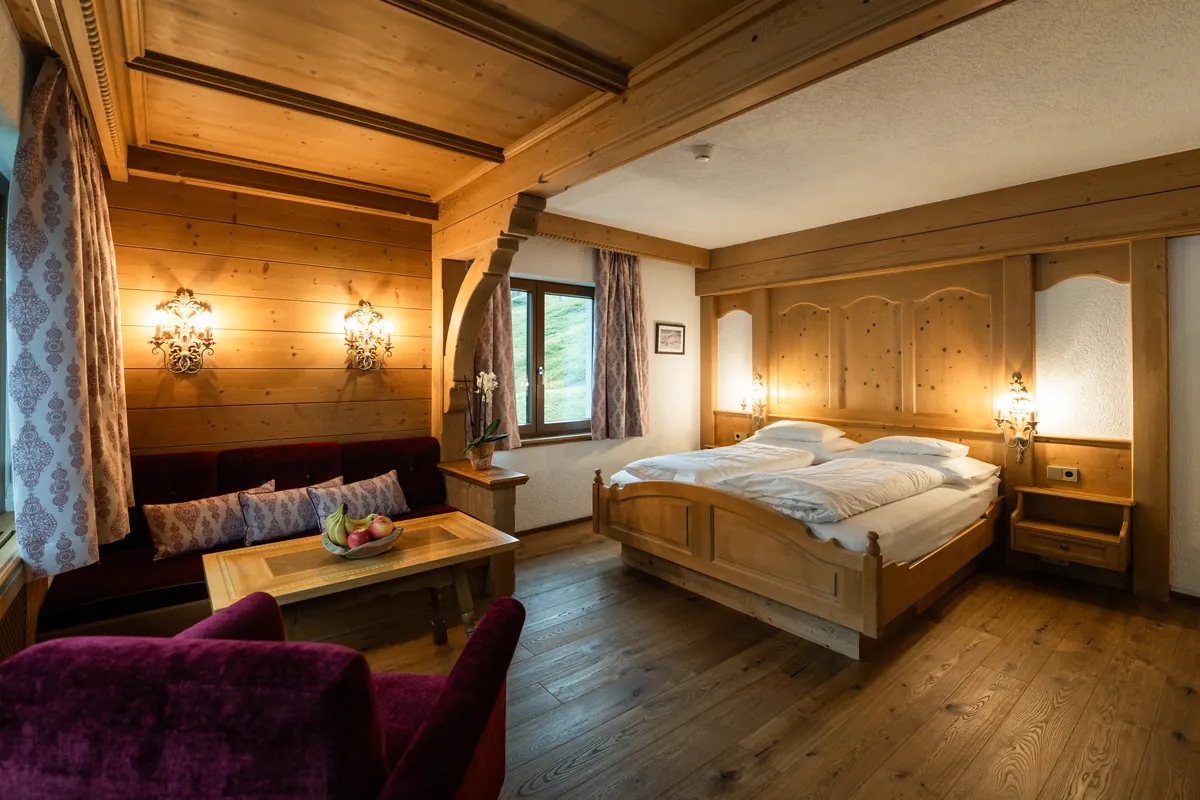 Habitación doble Classic con madera de pino cembro y rincón de estar del Hotel Ulli